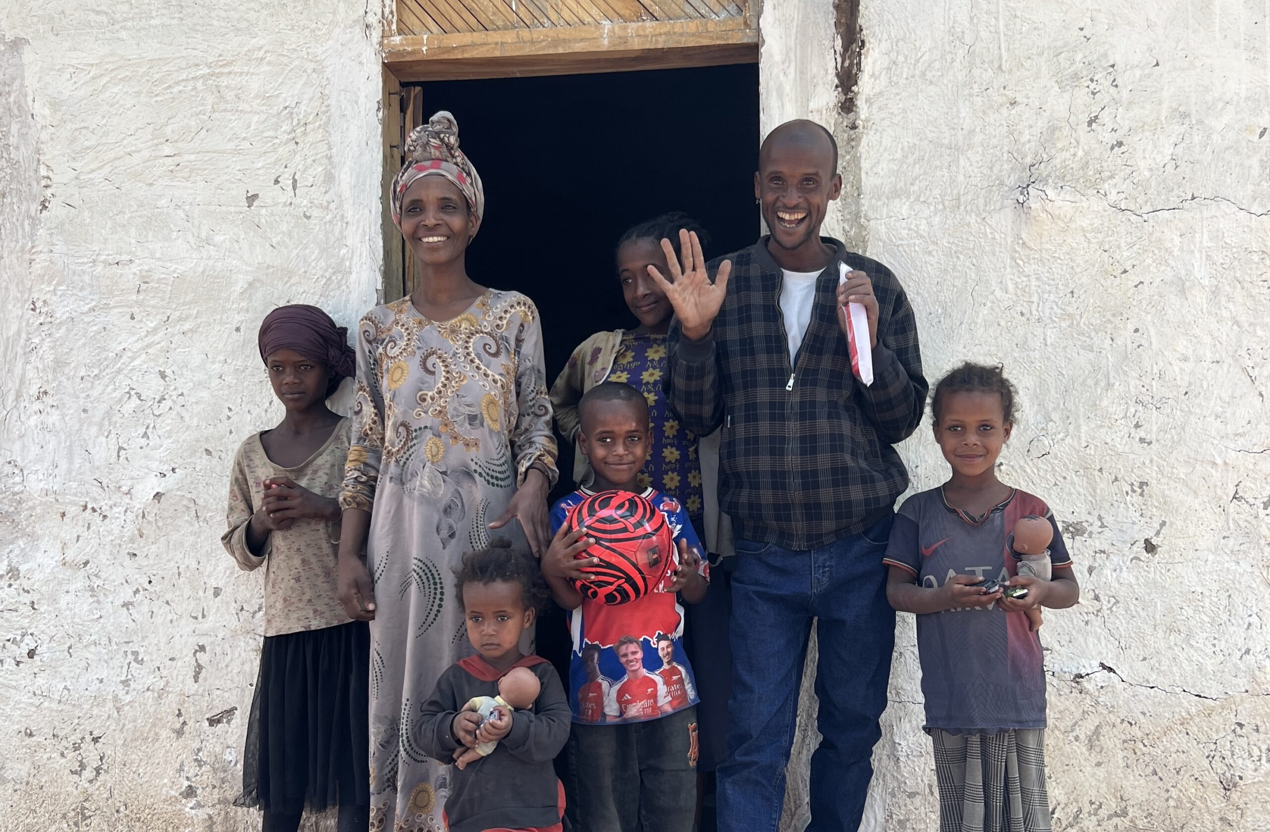 Sidama, Ethiopia family smiling outside new safe home—Hawassa Hope Building Hope initiative providing secure housing for vulnerable families.